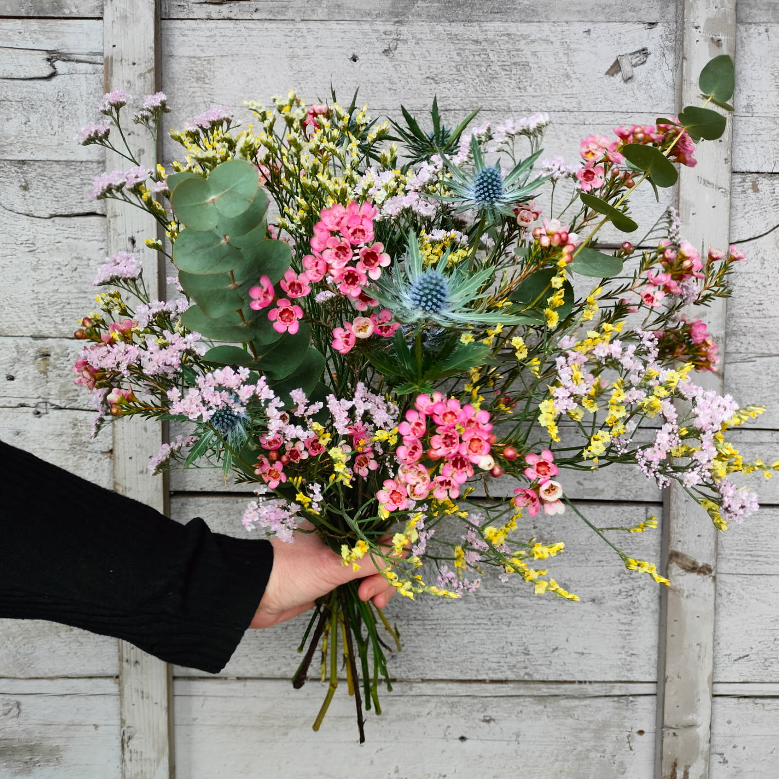 Hænder der holder mobiltelefon og tager billede af blomster